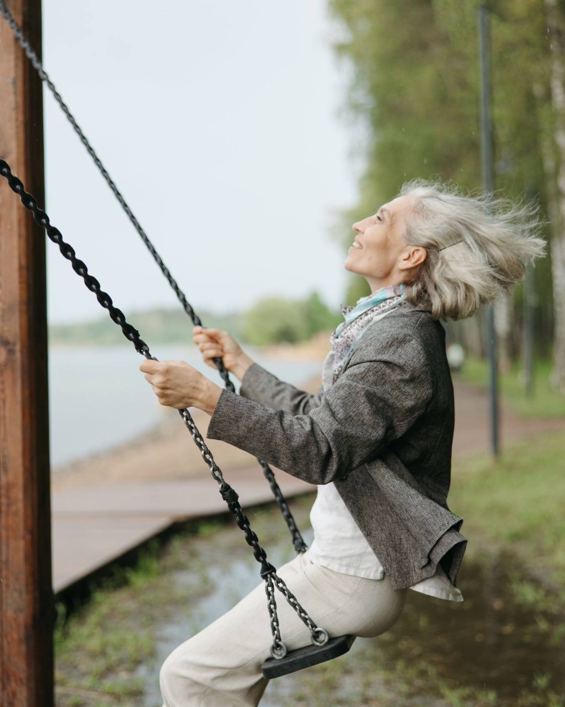 A woman on a swing by the water on an overcast day